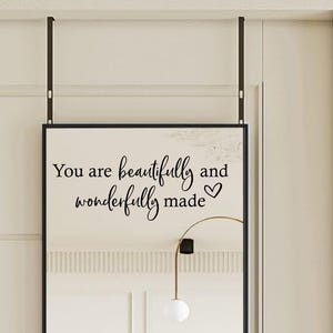 Op de afbeelding: Een zwarte spiegel met een witte achtergrond en de tekst "You are beautifully and wonderfully made" met een hartje.