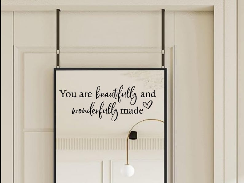 Op de afbeelding: Een zwarte spiegel met een witte achtergrond en de tekst "You are beautifully and wonderfully made" met een hartje.