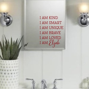 May include: A white bathroom mirror with a red vinyl decal that reads "I am kind, I am smart, I am unique, I am brave, I am loved, I am Elijah".