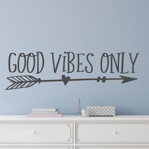 May include: A white dresser with two drawers and a black arrow with the text "GOOD VIBES ONLY" above it.