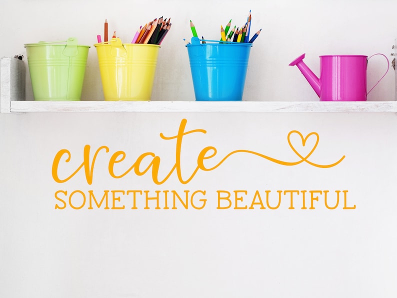 Pu&ograve; includere: Uno scaffale bianco con le parole "create something beautiful" in lettere arancioni. Ci sono quattro secchi colorati sullo scaffale, ognuno pieno di matite colorate. Un annaffiatoio rosa &egrave; sullo scaffale a destra.