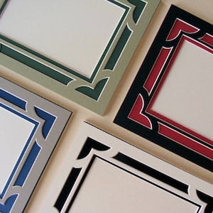 May include: Four picture frames with different colored borders. The frames are all the same size and shape, with a decorative design around the edge. The colors of the frames are green, blue, black, and red.