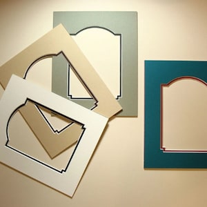 May include: Four different mat boards with an arched opening. The mat boards are in white, beige, green, and teal.