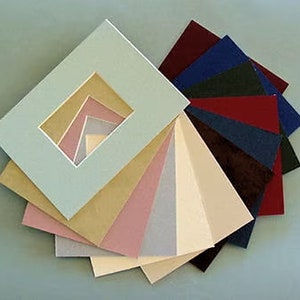 May include: A set of 10 different colored mat boards for framing pictures. The mat boards are arranged in a fan shape, with the lightest color at the top and the darkest color at the bottom. The mat boards are all the same size and have a square opening in the center.
