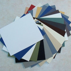 May include: A fan-shaped arrangement of 20 different colored cardstock paper sheets. The sheets are arranged in a gradient from white to dark brown.