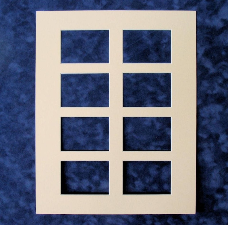 May include: A white mat with eight rectangular cutouts for displaying photos or artwork. The mat is designed to hold eight pictures in a grid pattern.