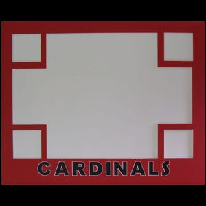 May include: A red and white picture frame with the word "CARDINALS" in black letters. The frame has a rectangular shape with four square cutouts in the corners and a large central opening.