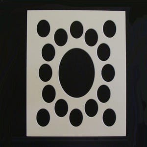May include: White square frame with 19 circular cutouts. The cutouts are arranged in a circle around a larger circular cutout in the center. The frame is made of a thick, white material.