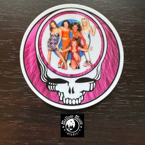 May include: A pink and white sticker with a skull and crossbones design. The skull has a pink and white swirl pattern. Inside the skull is a picture of five women. The sticker has the text "Mellow Moon Studio" at the bottom.