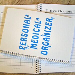 May include: A white spiral bound notebook with the words "Personal Medical Organizer" printed in blue. The notebook is open to a page with a grid pattern and the words "Eye Doctors" printed at the top.