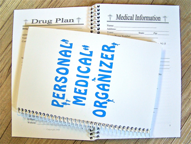 May include: A white spiral bound notebook with the words "Personal Medical Organizer" printed in blue. The notebook has a section labeled "Drug Plan" and another section labeled "Medical Information".