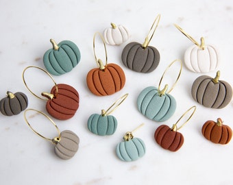 May include: A set of 12 pumpkin-shaped earrings in various colors, including teal, brown, gray, and white. The earrings are made of polymer clay and have a gold hoop.