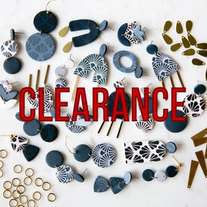 Puede incluir: Surtido de pendientes de cerámica azul y blanca con motivos geométricos y florales. Los pendientes se muestran sobre una superficie blanca con la palabra "CLEARANCE" en letras rojas.
