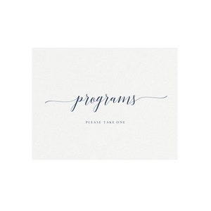 May include: A rectangular card with the word "programs" in elegant navy blue script. Below, in a smaller font, it reads "PLEASE TAKE ONE". The background is a textured off-white.