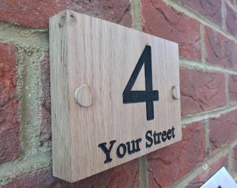 May include: A wooden house number sign with the number 4 and the text "Your Street" in black lettering. The sign is attached to a brick wall with two screws.