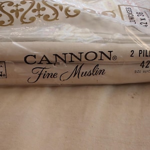 Może przedstawiać: Opakowanie dw&oacute;ch poszewek na poduszki Cannon Fine Muslin. Poszewki są białe, a opakowanie jest z przezroczystego plastiku. Tekst na opakowaniu brzmi "2 Poszewki na poduszki 106.68 x 91.44 cm".