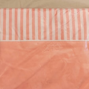 May include: A packaged Cannon Royal Family twin bed sheet measuring 72 by 108 inches. The sheet features a solid peach-colored bottom section and a white and peach striped top section, with a gold-toned label detailing the product specifications.