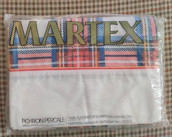 May include: A Martex twin flat sheet packaged in clear plastic. The sheet features a white base with a red, blue, and yellow plaid pattern at the top. Text on the packaging reads No-Iron Percale, Twin Flat Sheet for 39x75 in. mattress.