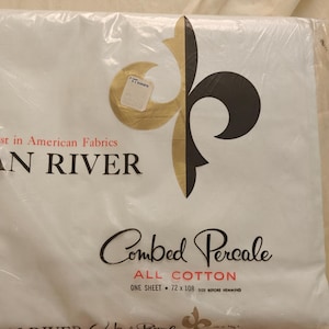 May include: A white Dan River brand bed sheet packaged in clear plastic. The label features a black and gold fleur-de-lis, the text First in American Fabrics, Dan River, Combed Percale, All Cotton, and the dimensions 72 x 108 inches.