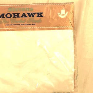 May include: A packaged white sheet set. The packaging is clear plastic with a brown and cream-colored label that reads "Stevens MOHAWK" in dark brown text. The sheet set is labeled "ONE SHEET 81 x 108 DOUBLE BED".