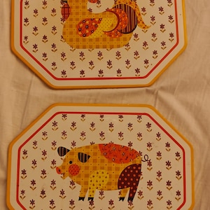 May include: Two octagonal metal trays with yellow borders. The top tray features a yellow checkered rooster with red and brown floral accents. The bottom tray displays a yellow checkered pig with similar red and brown floral patterns on its body.