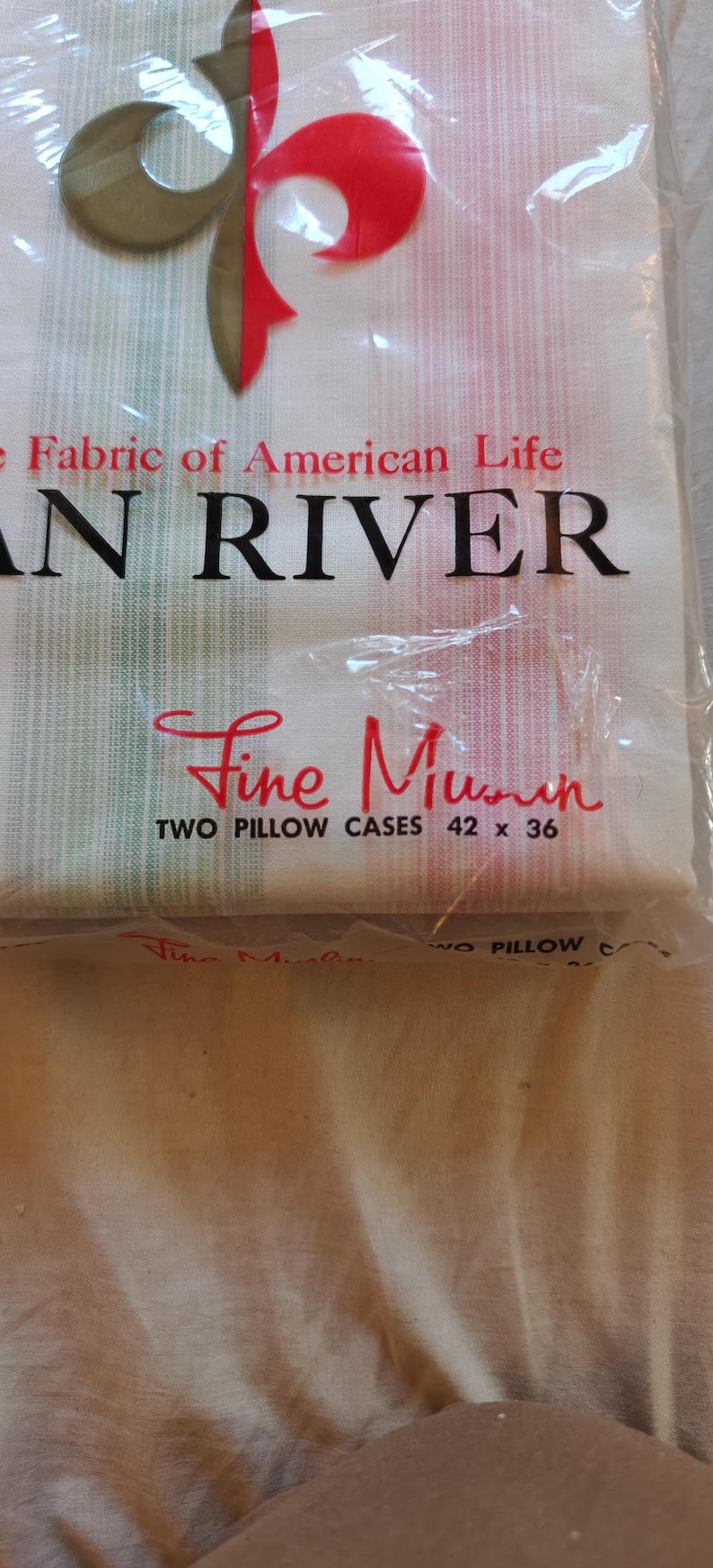 May include: A package of two "Fine Muslin" pillowcases, 42 x 36 inches, with the text "AN RIVER" and "Fabric of American Life". The packaging has a red, green, and brown design.