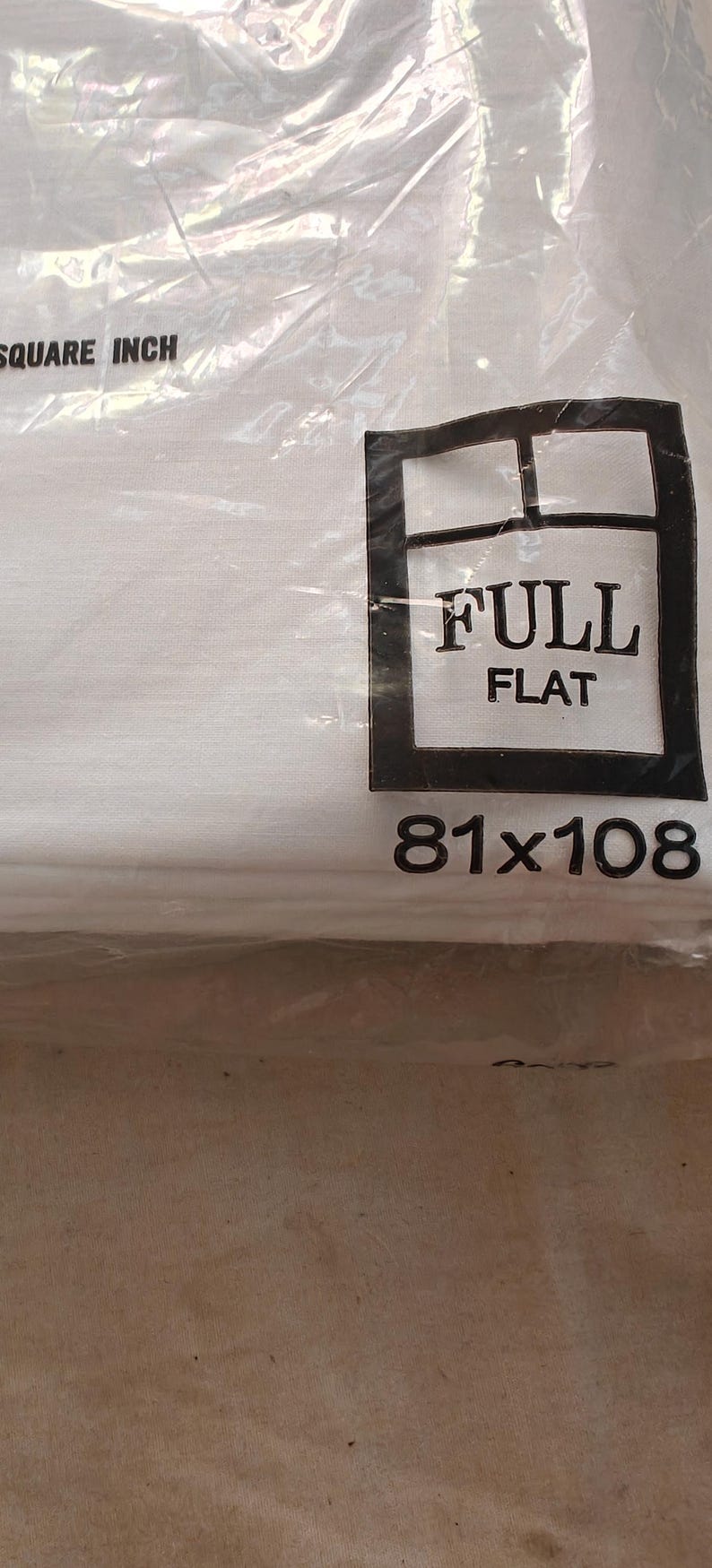 K&ouml;nnte beinhalten: Ein wei&szlig;es, flaches Spannbettlaken, verpackt in durchsichtigem Kunststoff. Die Verpackung tr&auml;gt den Text "FULL FLAT" in einem schwarzen Rechteck mit den Ma&szlig;en "206x274cm" darunter.