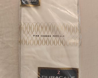 May include: A package of two white Fieldcrest Duracale pillowcases in clear plastic packaging. The label features the text Fieldcrest, Fine Combed Percale, and 2 Duracale Pillow Cases with a gold decorative oval pattern across the center.