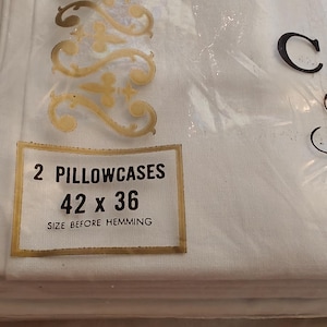 Może przedstawiać: Opakowanie dw&oacute;ch białych poszewek na poduszki. Etykieta wskazuje rozmiar 106,68 x 91,44 cm przed obszyciem. Nazwa marki "CANNN" i "Fine M" są widoczne czarnym pismem.