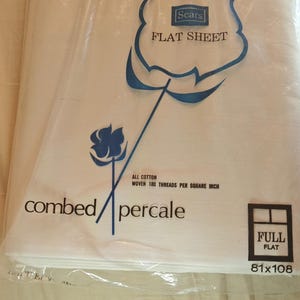 K&ouml;nnte beinhalten: Ein wei&szlig;es Bettlaken in einer Plastikverpackung. Die Verpackung zeigt das Sears-Logo und die Worte "FLAT SHEET". Das Laken ist mit "combed percale" und "Full Flat 206x274cm" beschriftet.