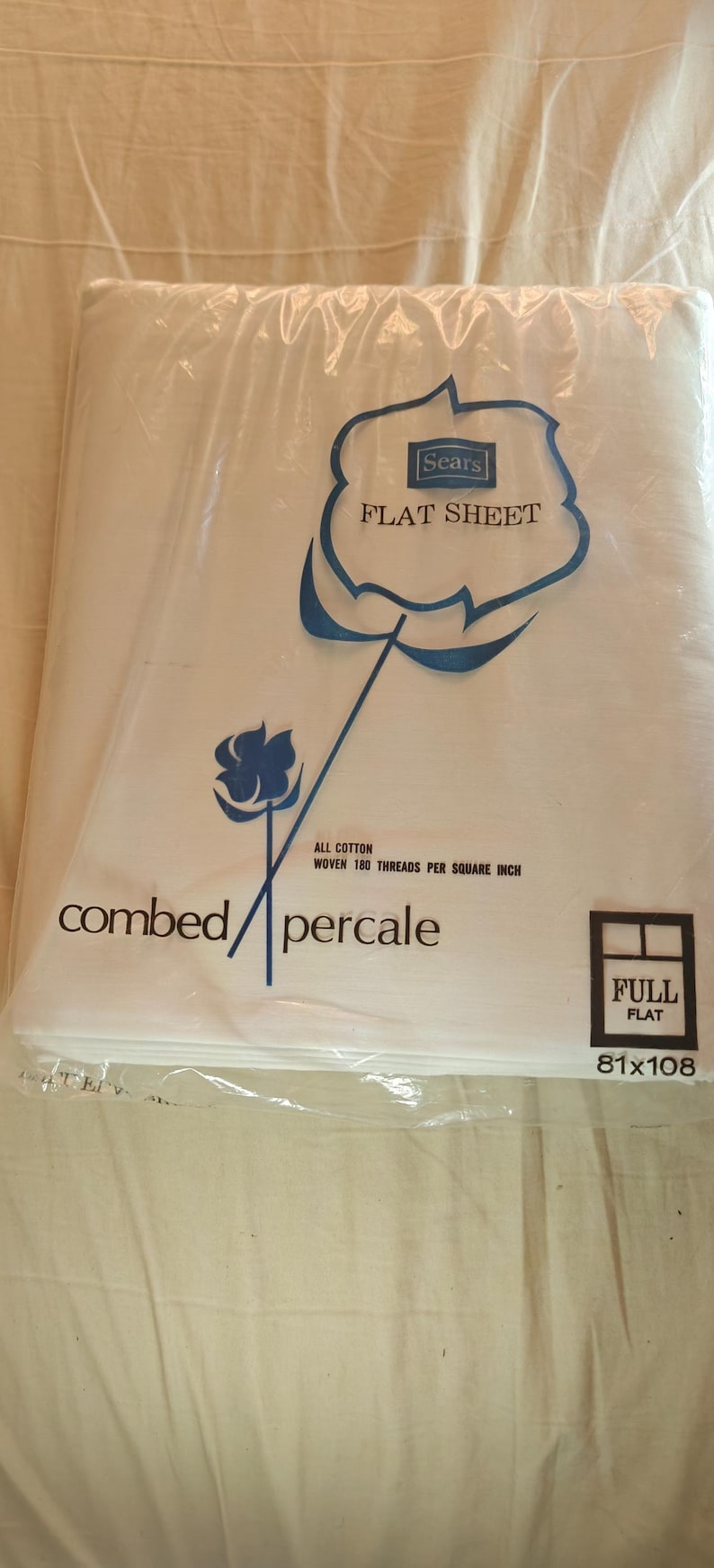 K&ouml;nnte beinhalten: Ein wei&szlig;es Bettlaken in einer Plastikverpackung. Die Verpackung zeigt das Sears-Logo und die Worte "FLAT SHEET". Das Laken ist mit "combed percale" und "Full Flat 206x274cm" beschriftet.