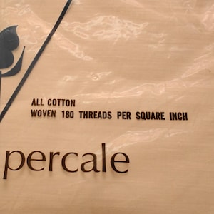K&ouml;nnte beinhalten: Verpackung eines flachen Bettlakens aus Baumwoll-Perkal. Die transparente Verpackung zeigt die Aufschrift &bdquo;FLAT SHEET&ldquo; und &bdquo;percale&ldquo;. Das Laken ist mit 180 F&auml;den pro Quadratzoll gewebt.