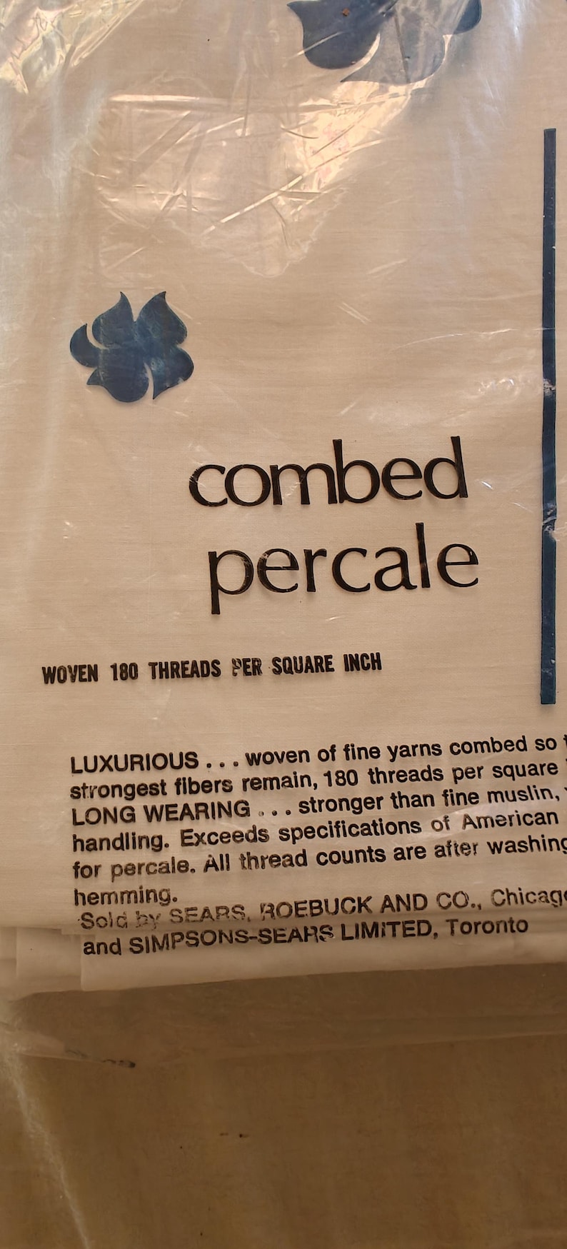 K&ouml;nnte beinhalten: Verpackung f&uuml;r gek&auml;mmten Percale-Stoff mit dem Text "gewebt 180 F&auml;den pro Quadratzoll". Das Design umfasst ein blaues Blumenmuster und den Text "Luxuri&ouml;s..." und "Langlebig..."