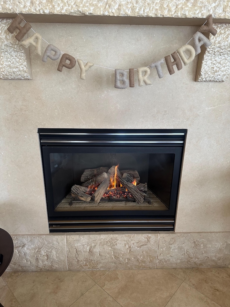 May include: A fireplace with a lit fire and a felt banner that reads "Happy Birthday" hanging above it.