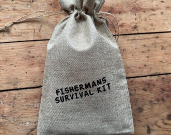 May include: A beige burlap drawstring bag with the text "Fishermans Survival Kit" printed in black.