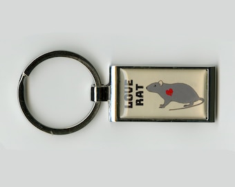 May include: A silver key ring with a rectangular charm featuring a grey rat with a red heart on its chest. The charm has the text "LOVE RAT" printed on it.