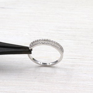Pode incluir: Um anel de prata com duas fileiras de pequenas pedras transparentes.