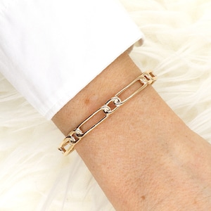 Könnte beinhalten: Ein goldenes Kettenarmband mit einem dicken, verlinkten Design.