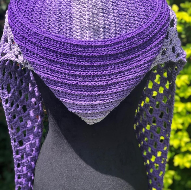 May include: A purple and gray ombre crochet shawl with a lacy design. The shawl is draped over a black mannequin.