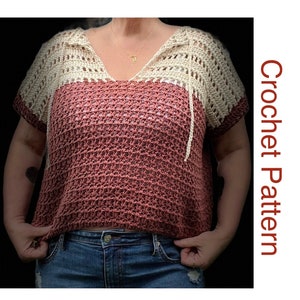 May include: A crochet top with a white crocheted hood and a pink and white ombre design. The top has short sleeves and a v-neck.