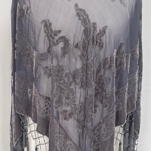 May include: A gray sheer shawl with a floral velvet pattern and beaded fringe.