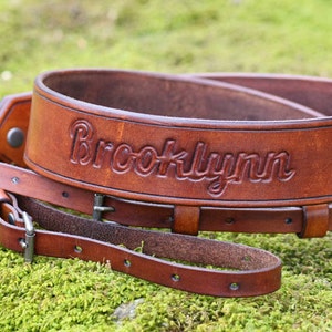 May include: A brown leather camera strap with the name "Brooklynn" embossed on it.