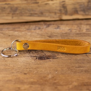 May include: A yellow leather keyring with a silver ring and the name "Jess" embossed on the leather.