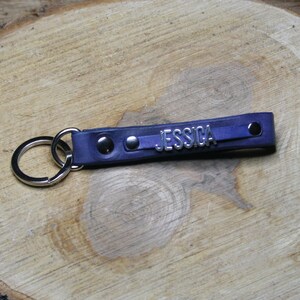 May include: A blue leather keychain with a silver metal ring and the name "JESSICA" embossed on the leather.