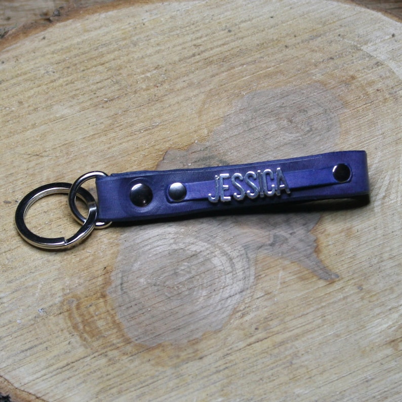 May include: A blue leather keychain with a silver metal ring and the name "JESSICA" embossed on the leather.
