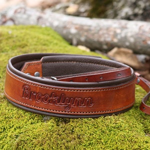 May include: A brown leather camera strap with the name "Brooklynn" embossed in the leather.