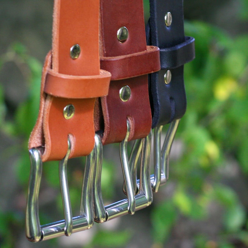 May include: Three leather belts with silver buckles. The belts are brown, dark brown, and black.
