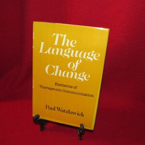 May include: A yellow book titled "The Language of Change: Elements of Therapeutic Communication" by Paul Watzlawick.