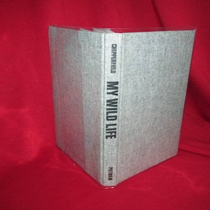 May include: A gray hardcover book with the title "MY WILD LIFE" by CHIPPERFIELD. The book is on a red surface.