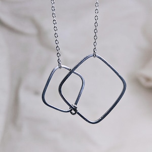 May include: A silver necklace with two interlocking square shapes.
